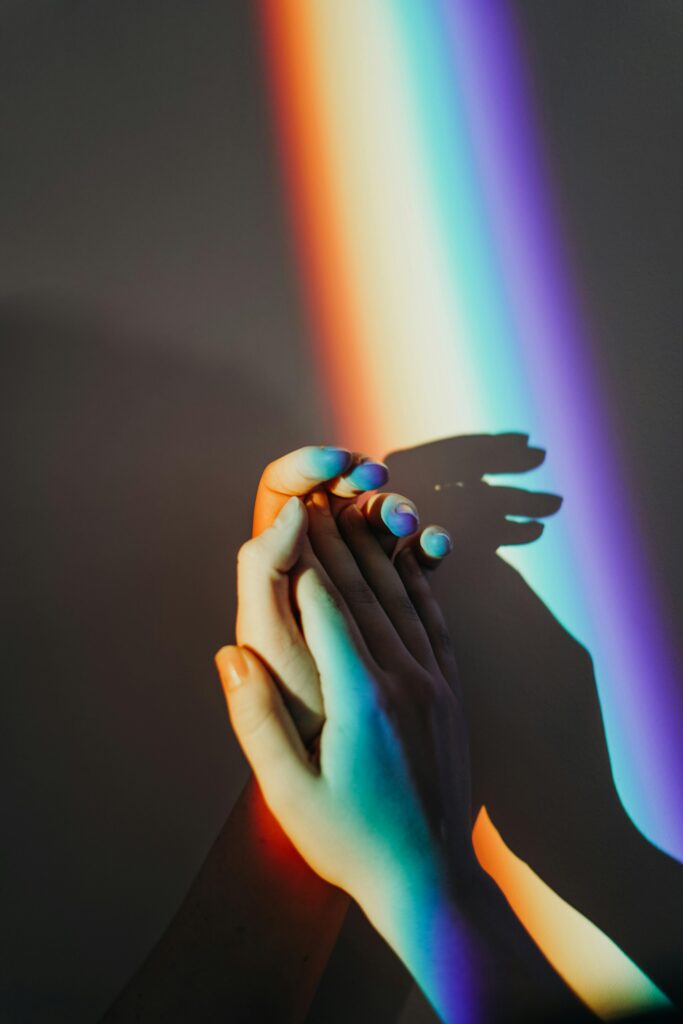 pexels-photo-3693914-3693914 Artistic representation of unity with hands holding under colorful rainbow light reflection.